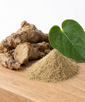 Getrocknete Kava-Wurzelstücke, Pulverhäufchen und grünes Blatt auf einem Holzbrett